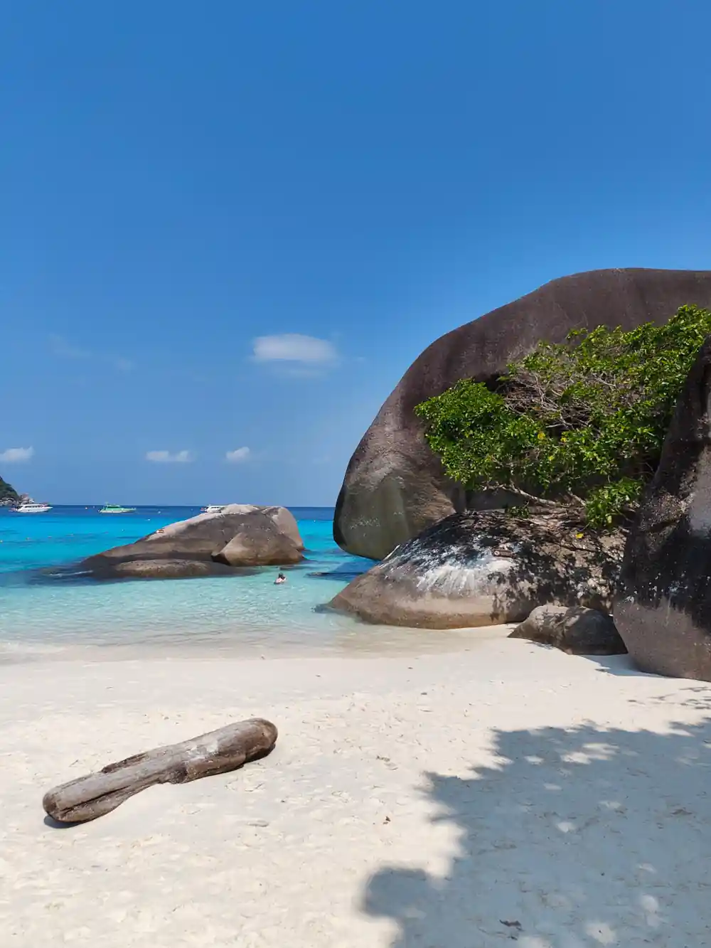 Granite rocks in shallow turquoise water and white sand beach