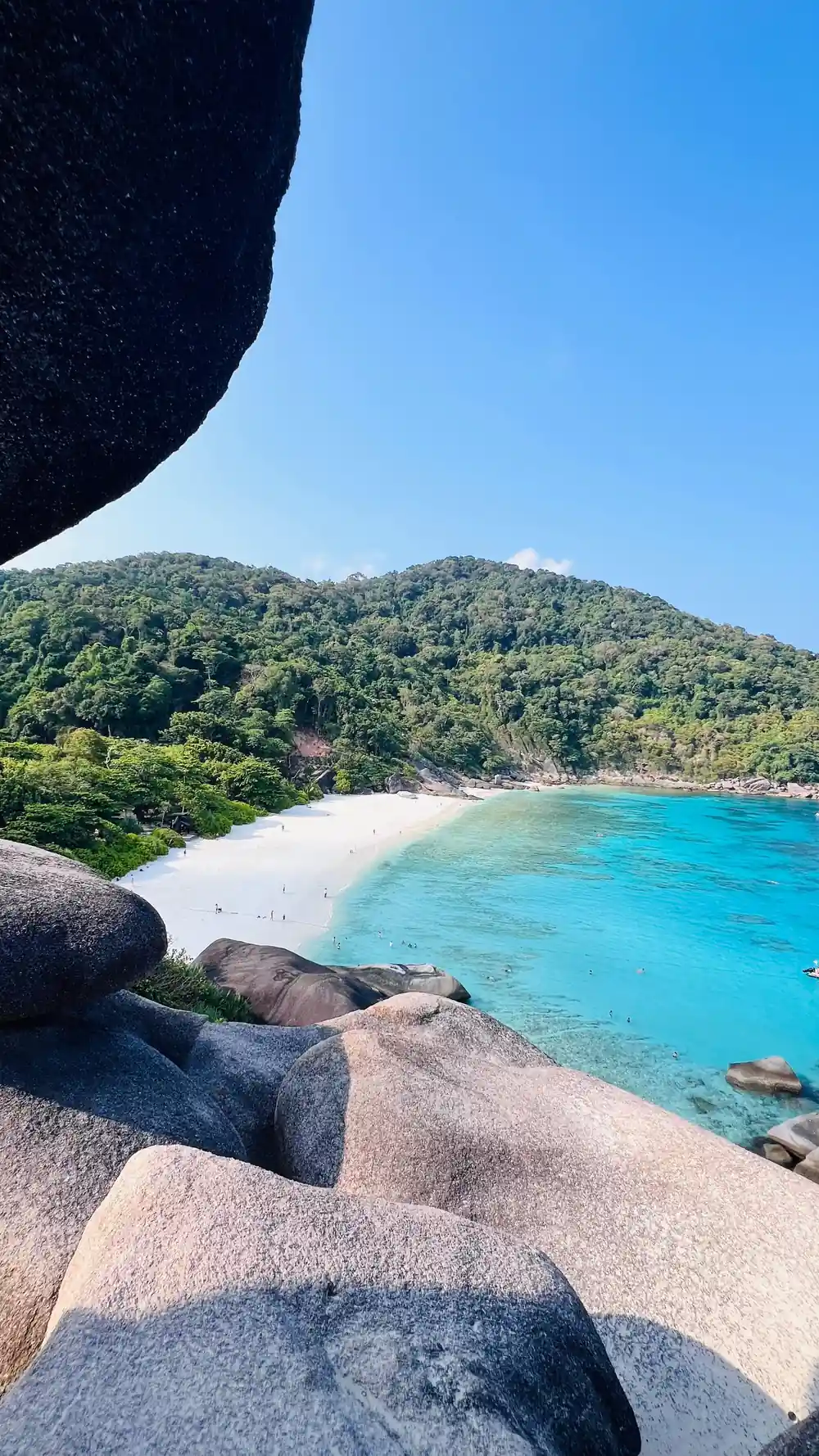 Large granite boulder overhanging white beach and turquoise water