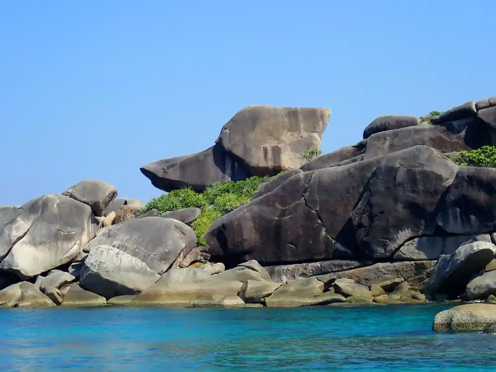 Large weathered granite rock formations above turquoise sea