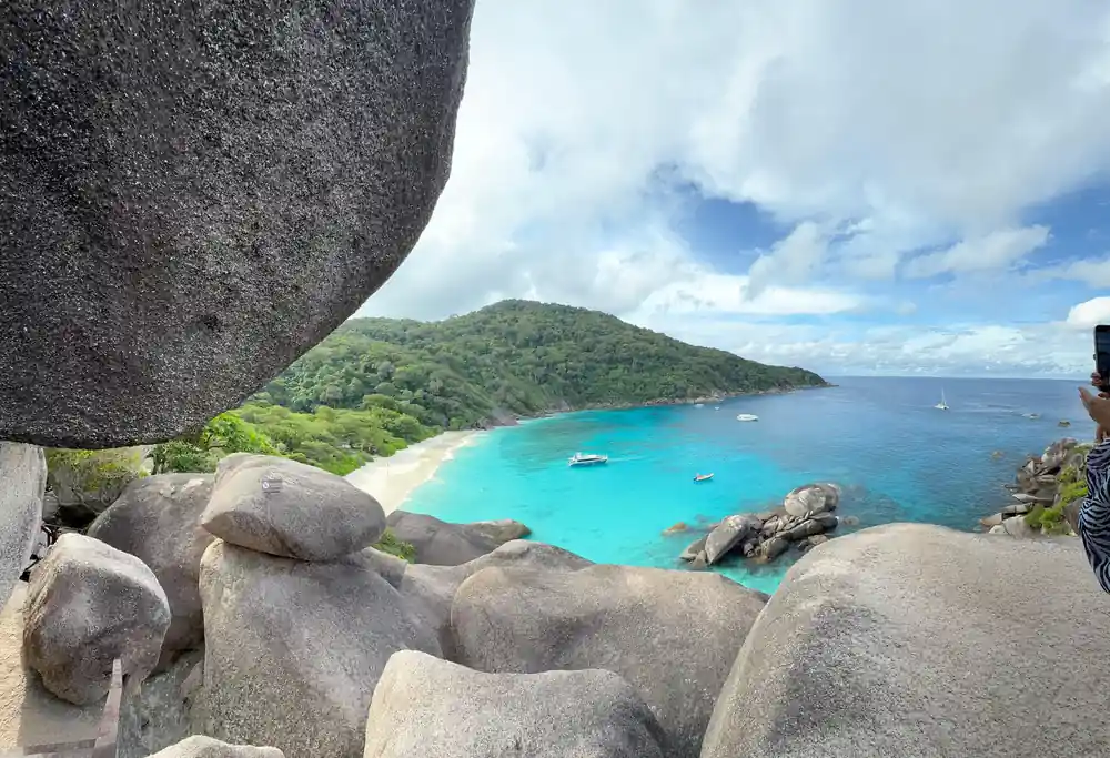 Rocky boulders framing turquoise bay with white sand