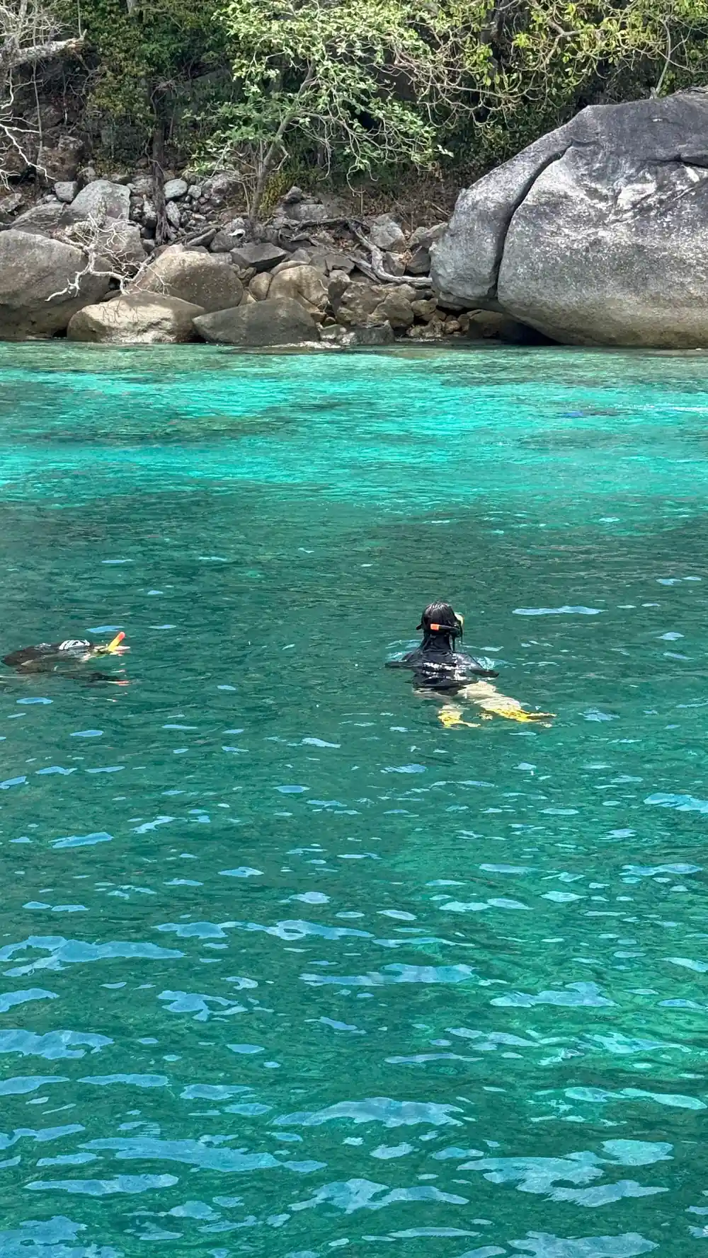 Snorkeler in turquoise water near granite rocks