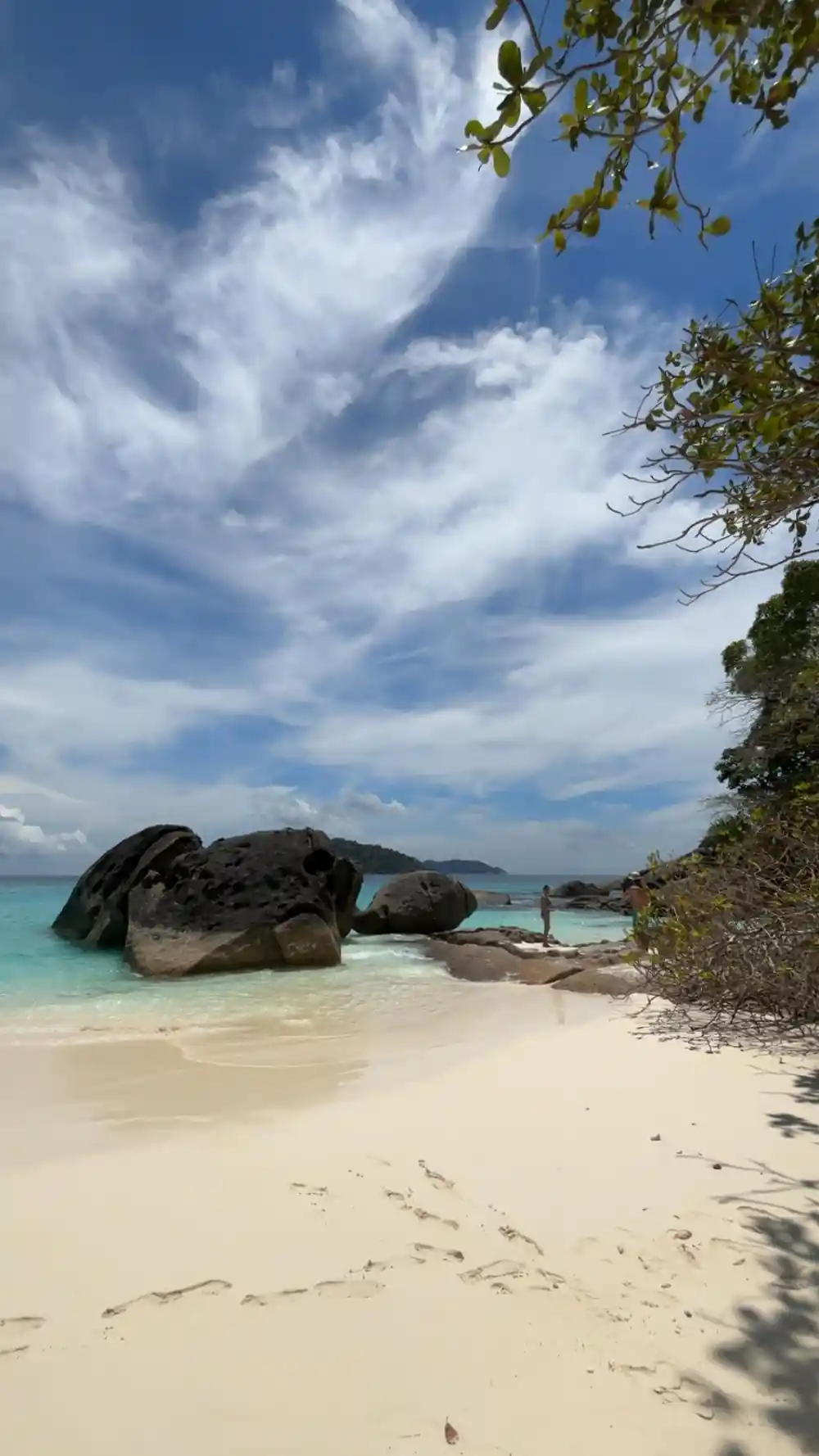 White sand beach with large black rock formations and turquoise water